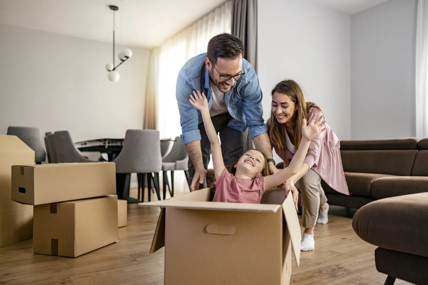 Herzensnah by Tanita Englisch -  Familiäre Unterstützung -Eine Familie spielt in einem Wohnzimmer inmitten von Umzugskartons.